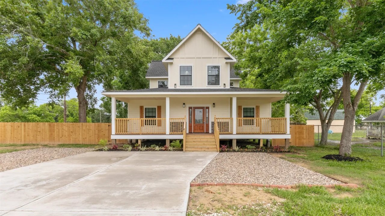 Daytime front exterior showing covered porch, board-and-batten gable, and white horizontal siding
