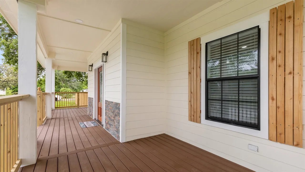 Covered wraparound front porch with composite decking and stained-wood accent panels