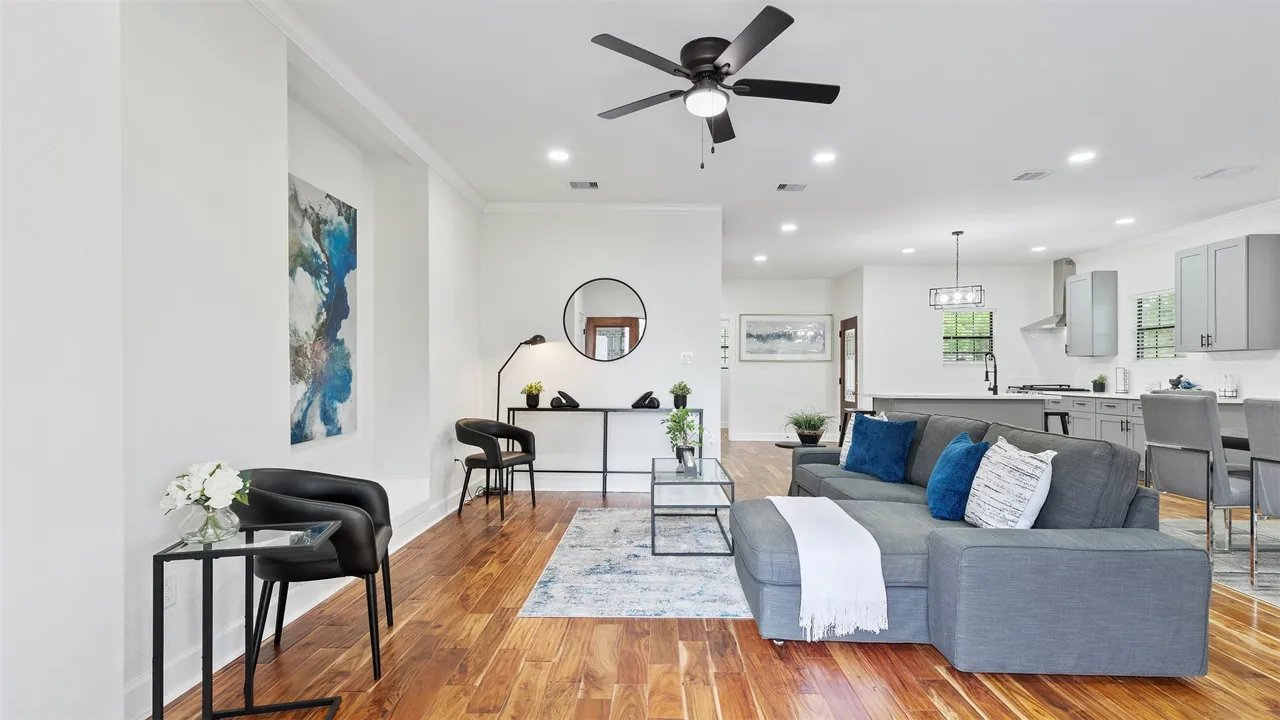 Open-concept living room with engineered hardwood, ceiling fan, and views toward the kitchen