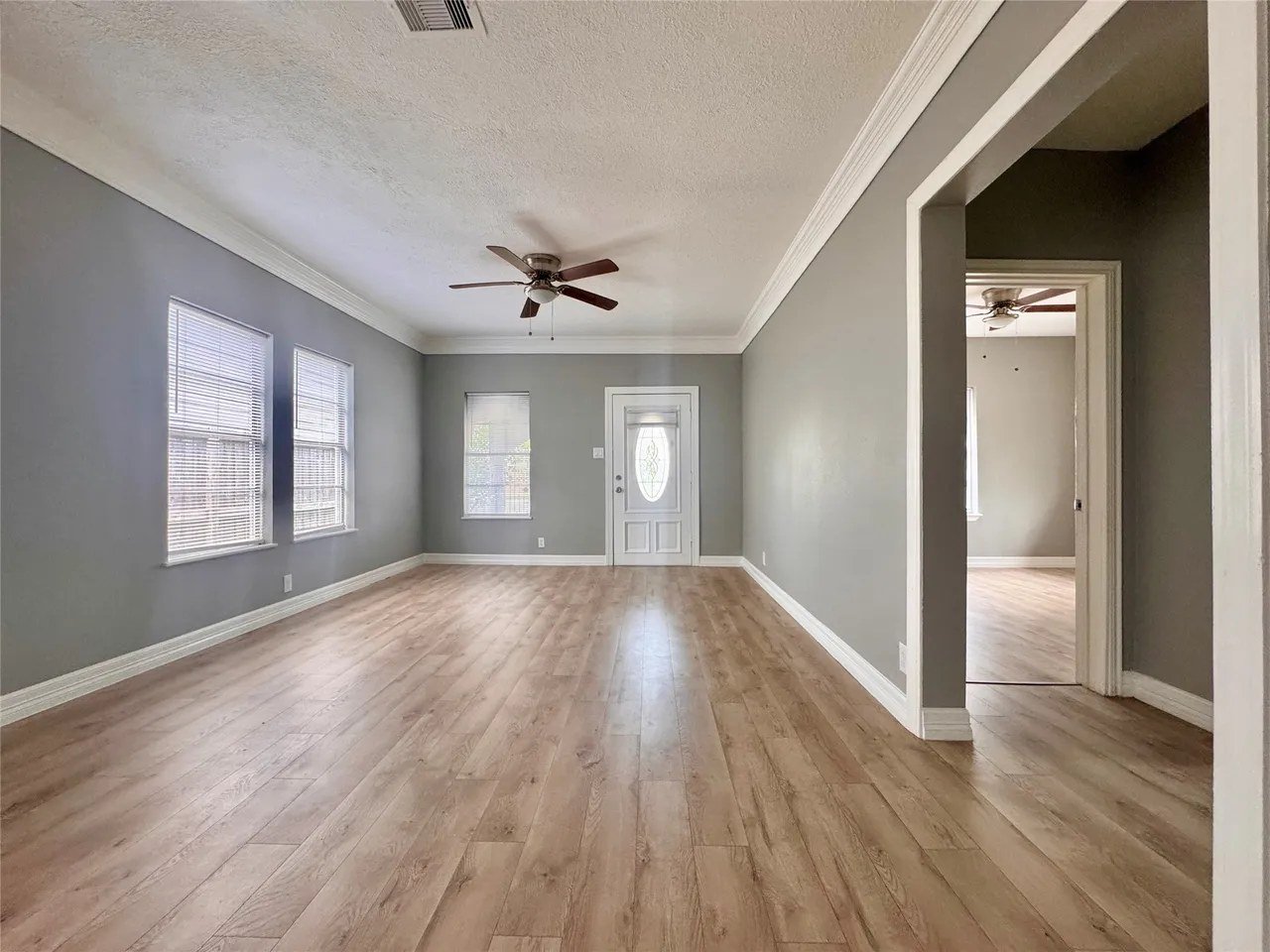 Front entry living room with oval-glass front door, ceiling fan, and laminate flooring