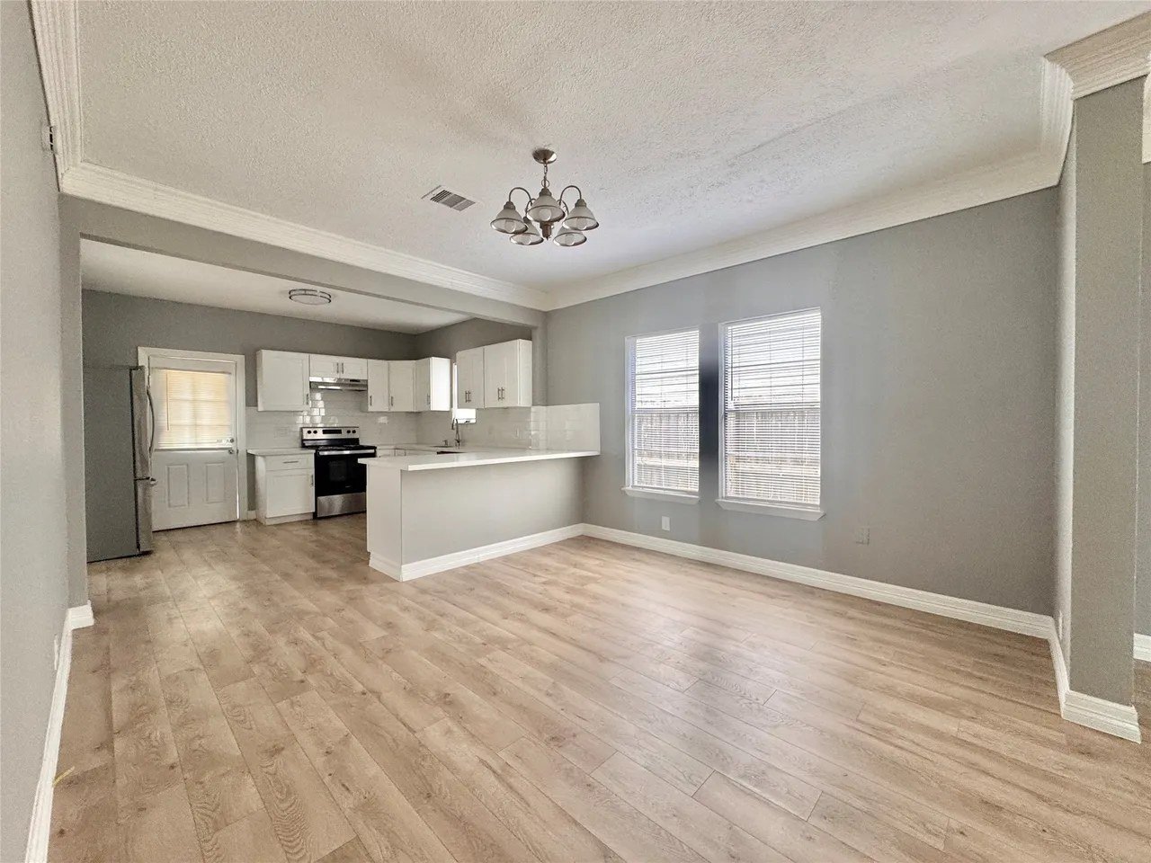 Open dining and family layout with laminate flooring and chandelier