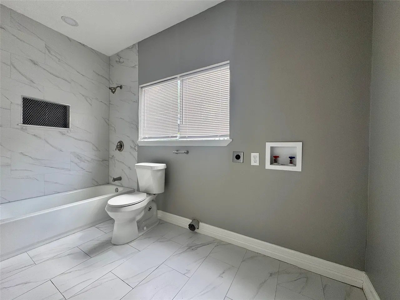 Full bathroom — closer angle on the tub/shower combo and laundry hookup recess
