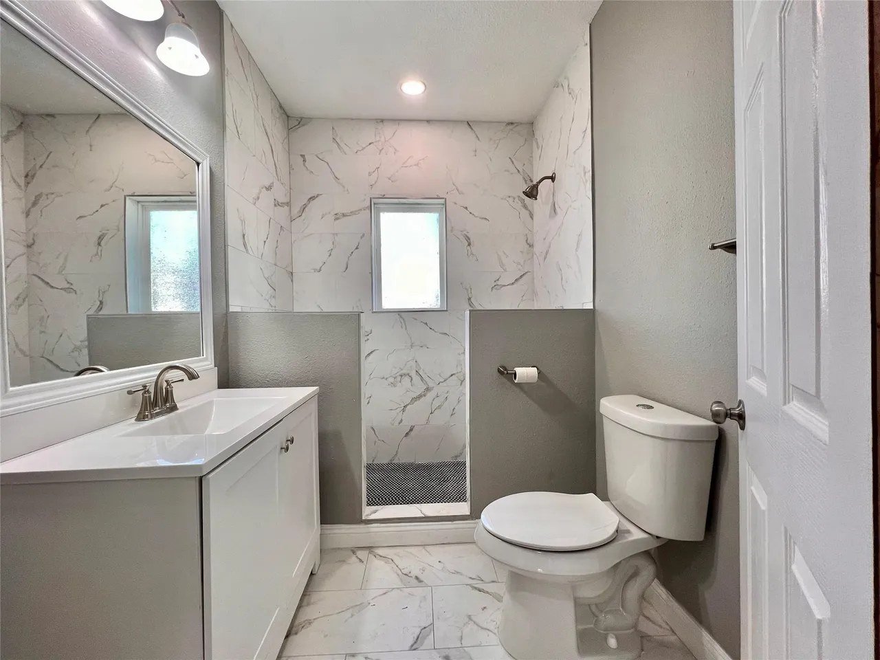 Second bathroom with oversized stand-up walk-in shower in marble-look tile
