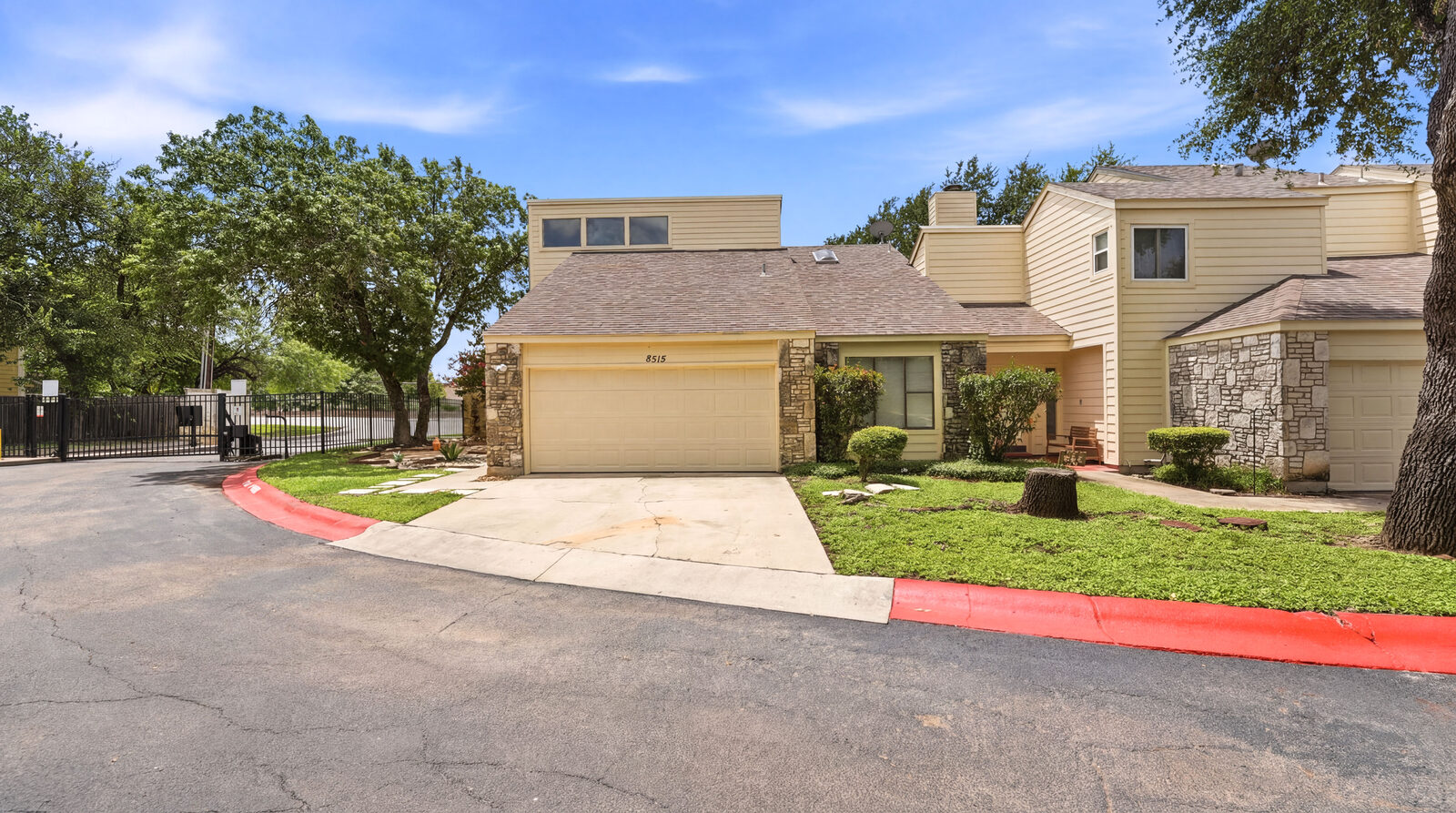Front exterior of 8515 Echo Creek Lane, San Antonio TX — two-story townhome with attached two-car garage, address number visible, gated community fence in background