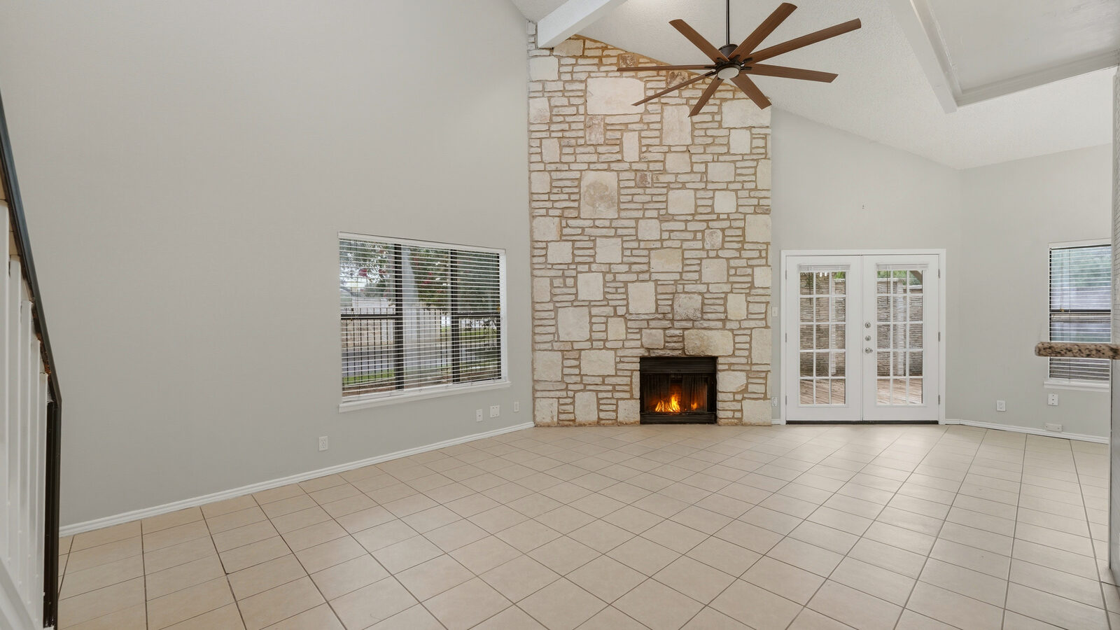 Entry / living area with sputnik chandelier, stone fireplace, and French doors to the back deck